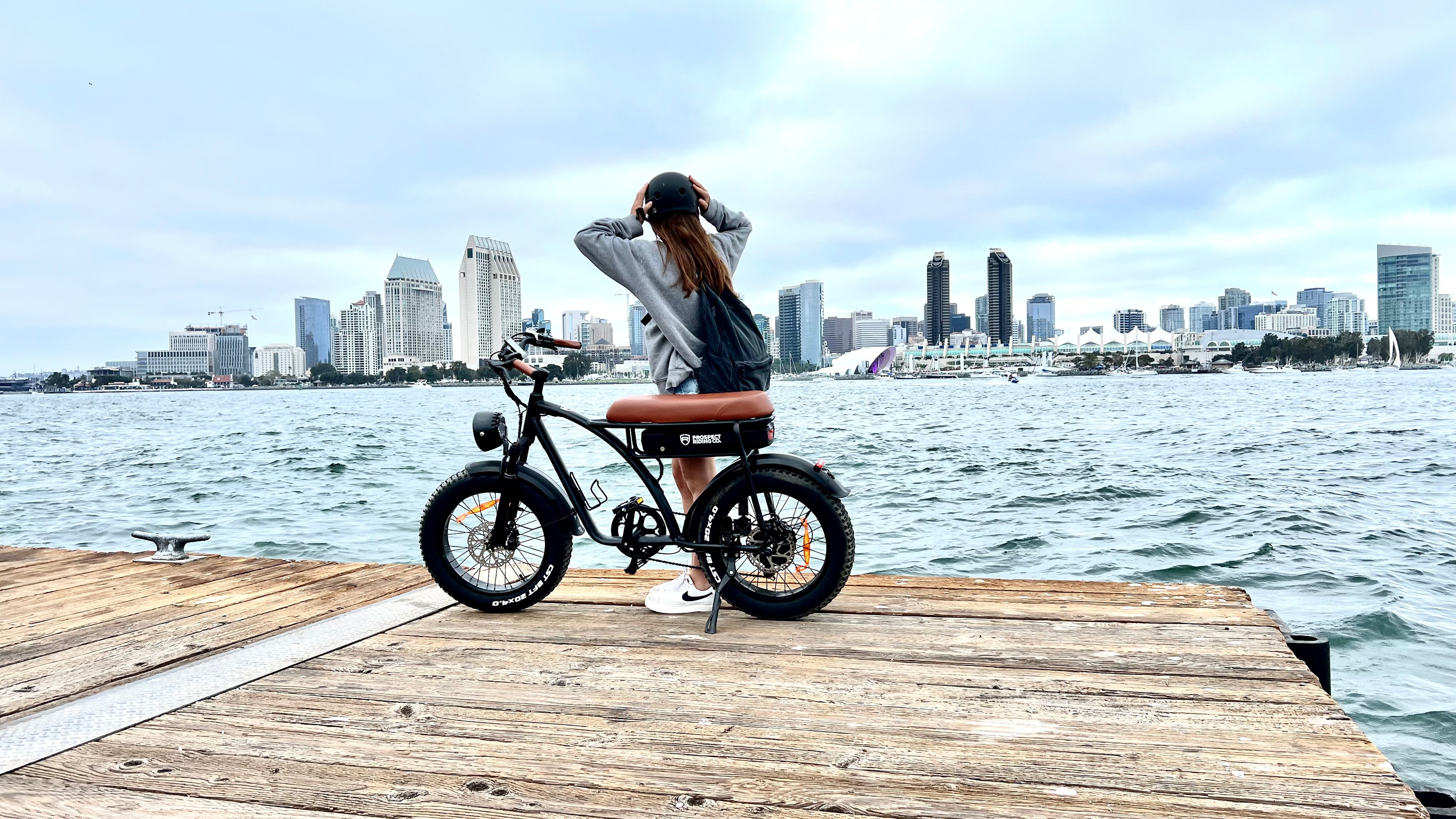 Laguna e-bike on the Coronado Ferry Landing with a girl looking on the big city skyline